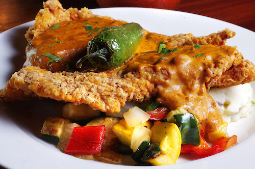 Breaded cutlet with brown gravy and a roasted pepper, sautéed zucchini and peppers, and mashed potatoes