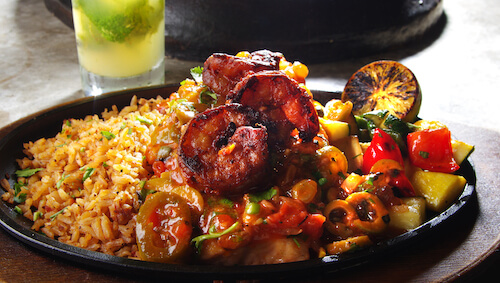 Skillet of Spanish rice, grilled shrimp and sautéed peppers with a charred lime and a mojito