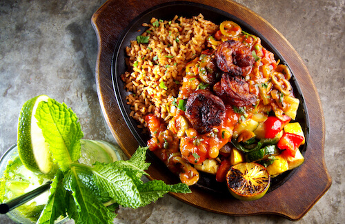 Overhead view of a skillet with rice, shrimp and vegetables beside a mint and lime drink